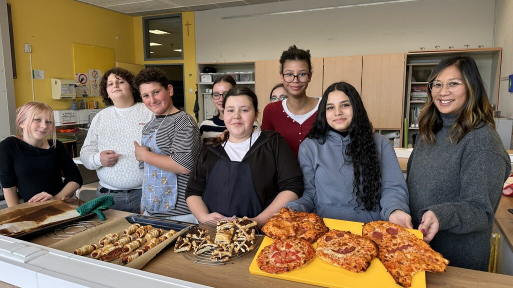 Teamarbeit mit Geschmack: Cerena Wohlfeld und ihre HuS-Gruppe nach dem Backen kreativer Halloween-Pizzen – ein Unterricht, der allen Spaß macht!
