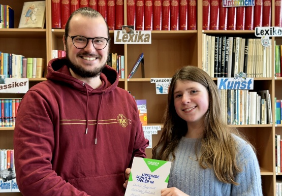 Der Vorsitzende der Fachschaft Deutsch, Thomas Meyer, mit der Schulsiegerin Leonie Hupperich