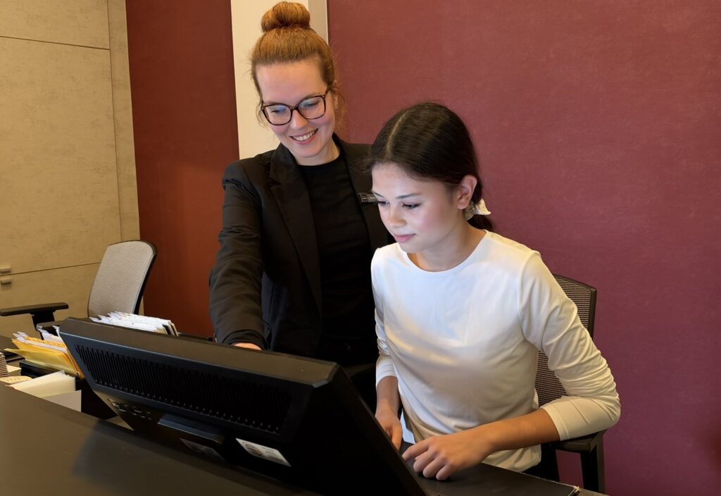 Valerie während ihres Praktikums im Hotel Villa St. Peter in Walporzheim, gemeinsam mit ihrer Betreuerin an der Rezeption, wo sie Einblicke in den Beruf der Hotelfachfrau erhielt.